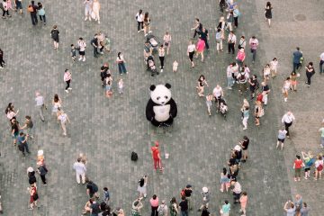 Una persona en disfraz de panda rodeada de personas en ropa casual
